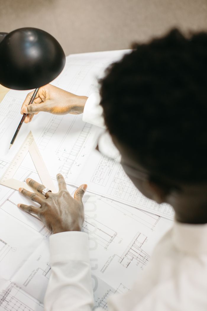 Focused architect working on blueprints at a modern workspace.
