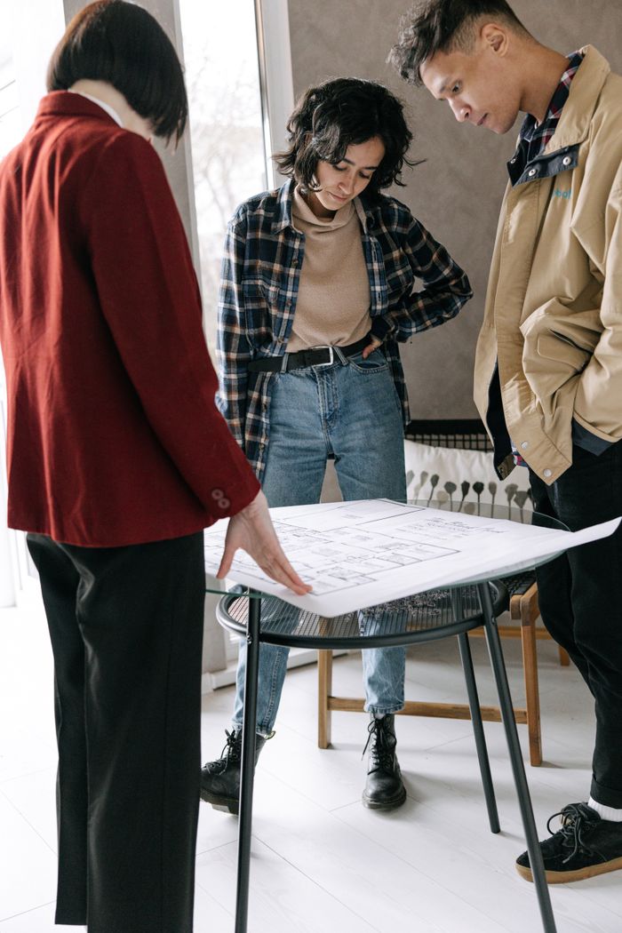 A young couple and real estate agent examining house plans indoors. Ideal for real estate and architecture themes.